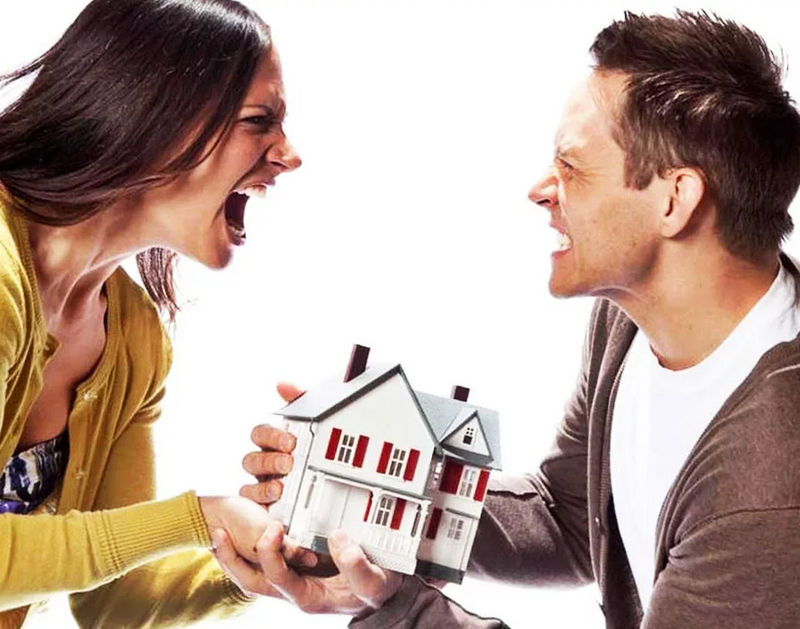 Мужчина и женщина кричат друг на друга и держат макет дома